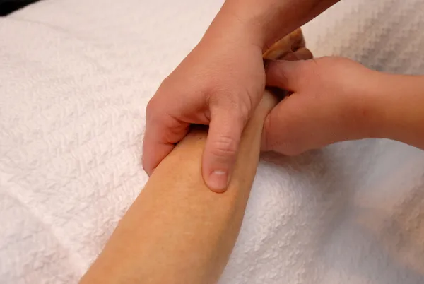 Kim's hands working on a client's arm during a massage session