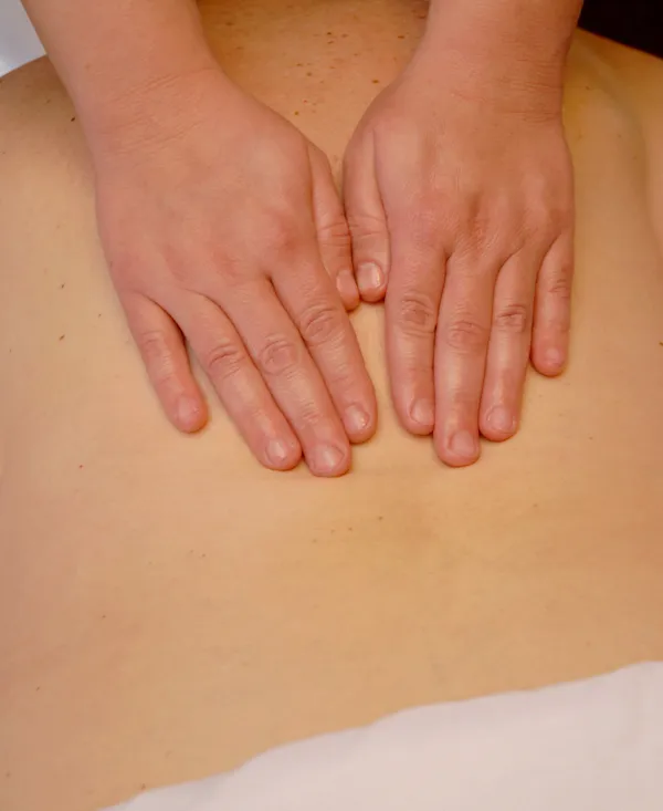 Hands performing a Swedish massage on a client's back